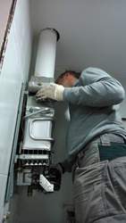 Montaje de calentador de gas para vivienda, canalización de salida de gases quemados.